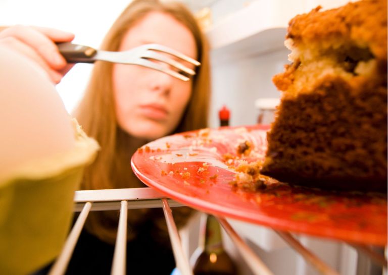 A woman with a fork about to eat cake